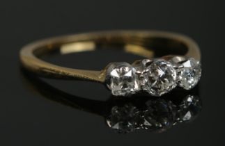 An 18ct gold three stone diamond ring. Having old cut diamonds, the central stone approximately 0.