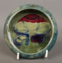 A William Moorcroft dish decorated in the Claremont design. With tubelined decoration depicting