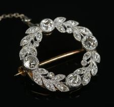 An 18ct gold and diamond wreath brooch. The four larger diamonds approximately 0.125ct each.