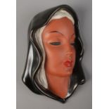 A Goldscheider wall mask portrait of a lady in head scarf. Impressed to back 7831. 22cm.