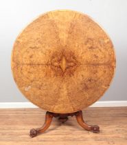 A Victorian walnut tilt top supper table with quarter veneered top and raised on carved tripod