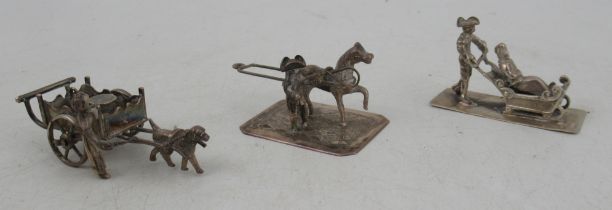 Three Dutch silver miniature models, figures pushed in a sledge, cart pulled by a dog with figure