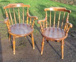 A pair of Windsor arm spindle back arm chairs, with a round seat, raised on turned legs united by