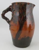 A large Longward pottery jug, decorated all round with trees and having a branch handle, signed to