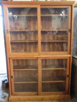 A pine double bookcase, with sliding glazed doors and adjustable shelves, height 78ins, width 50ins,