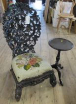 An Indian highly carved low chair, decorated with foliage, having a tapestry covered seat,