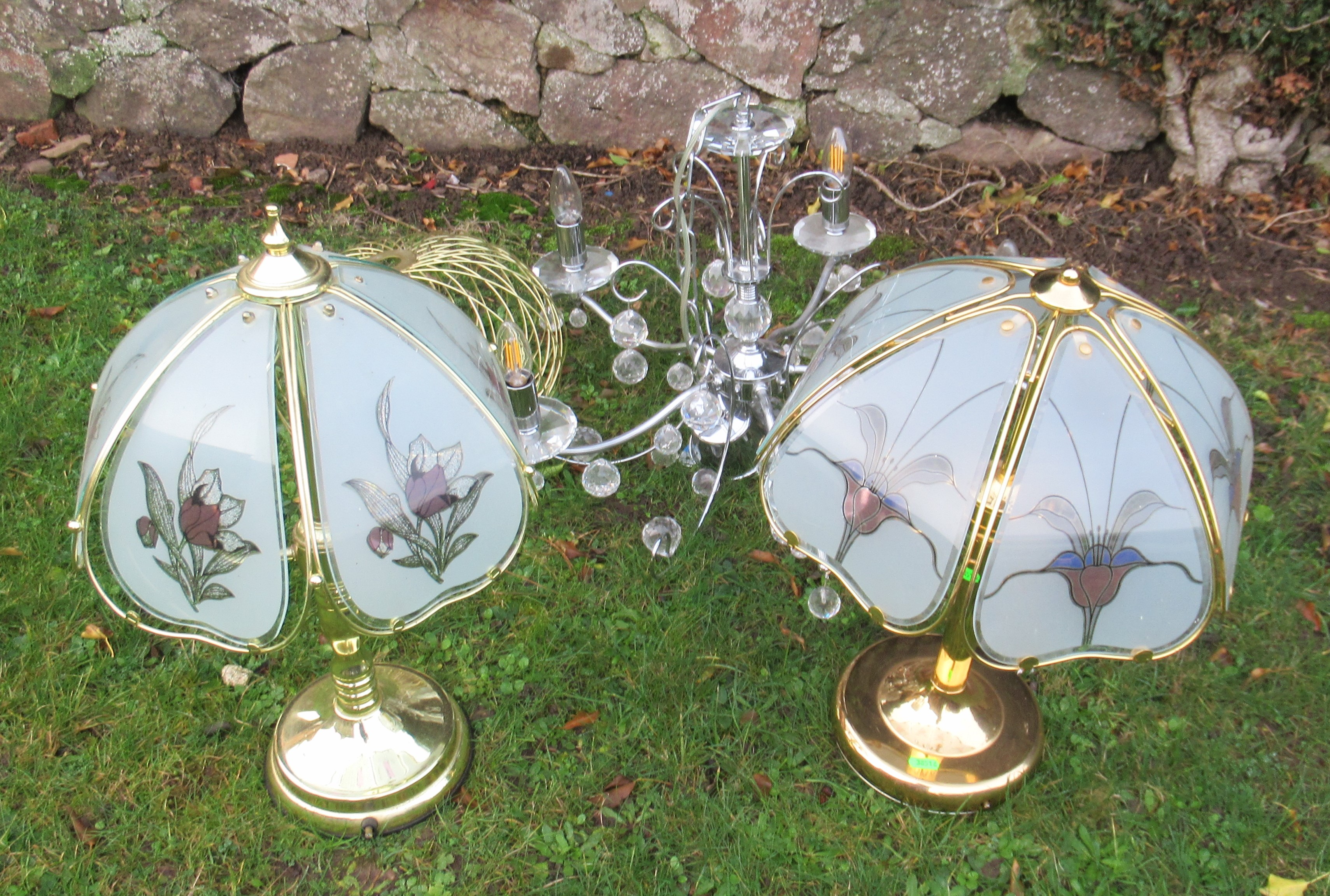 Two brass coloured table lamps, a chrome and glass hanging light fitting and a wire work shade