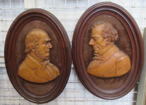 Two oval relief carved wooden portrait plaques, framed, height 18.5ins