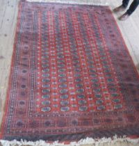 An Eastern design rug, the field with repeating motifs and a red ground, 101ins x 73ins