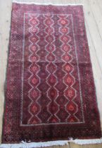 An Eastern design red ground rug, with repeating motifs to the field, 72ins x 41ins