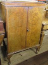 A Wilson & Gill London walnut veneered drinks cabinet, with hinged rising lid, over a pair of