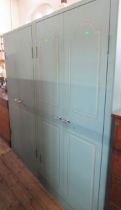 A pair of Triumph painted metal cabinets, with faux fielded panels to the doors, the insides
