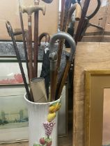 A collection of sticks, canes, one with silver mount, together with a vase/stick stand