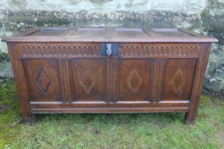 An oak coffer, with four lozenge panels below a four panel raising lid, width 58ins