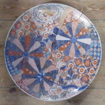 A large 19th century Japanese Imari charger, decorated with fans and panels of flowers, in the