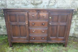 An Ecrol style oak sideboard, fitted with an arrangement of drawers, flanked by two cupboards, 58ins