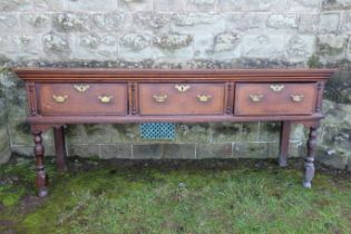 An early 19th century oak three drawer dresser base, raised on turned front legs, width 78ins