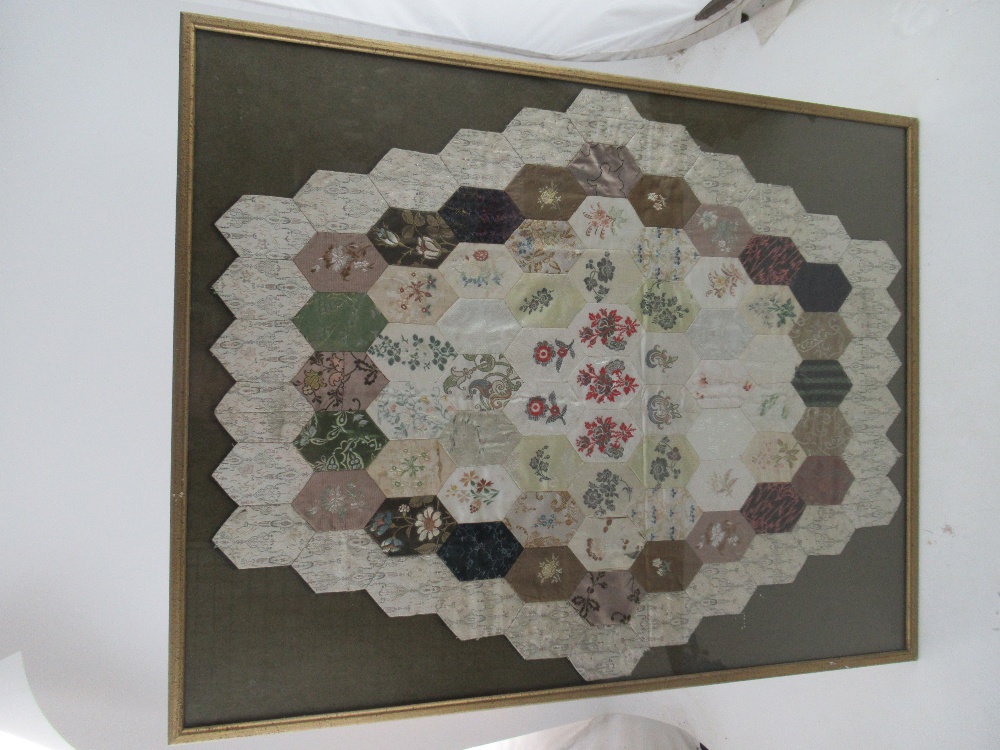 An 18th century patchwork quilt, with a hexagonal design, mounted in a glazed frame