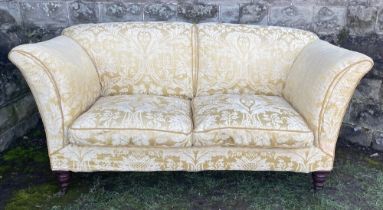 An antique Howard Grantley sofa raised on turned legs the casters, stamped Howard and Sons London,