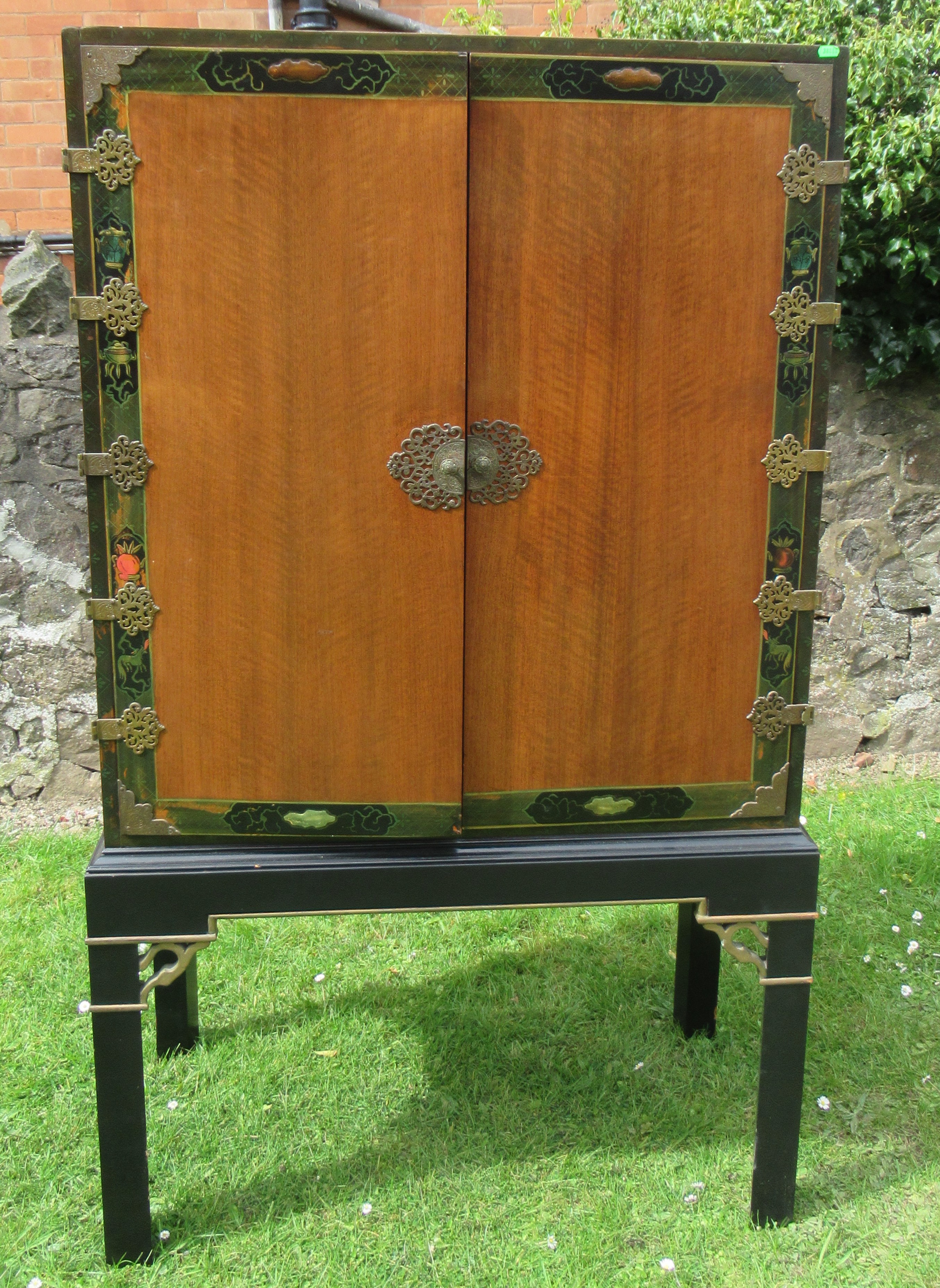 An Eastern design cabinet with painted decoration and applied gilt mounts raised on a stand, width