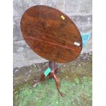 An Antique tilt top occasional table, possibly Yew wood,  raised on turned column and terminating in