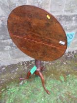 An Antique tilt top occasional table, possibly Yew wood,  raised on turned column and terminating in