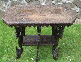 A carved oak occasional table, the top decorated with fielded panel of elephants and large raised on