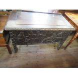 An antique oak coffer with plain raising lid the sides having fielded panels with carved decoration,