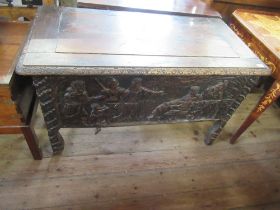 An antique oak coffer with plain raising lid the sides having fielded panels with carved decoration,