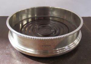 A silver wine coaster, with turned wooden base, diameter 5ins