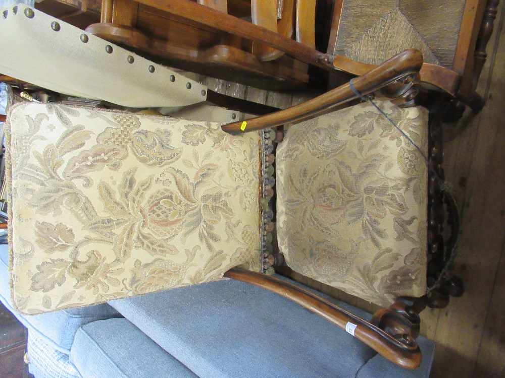 An antique open arm chair with tapestry back and seat raised on carved legs