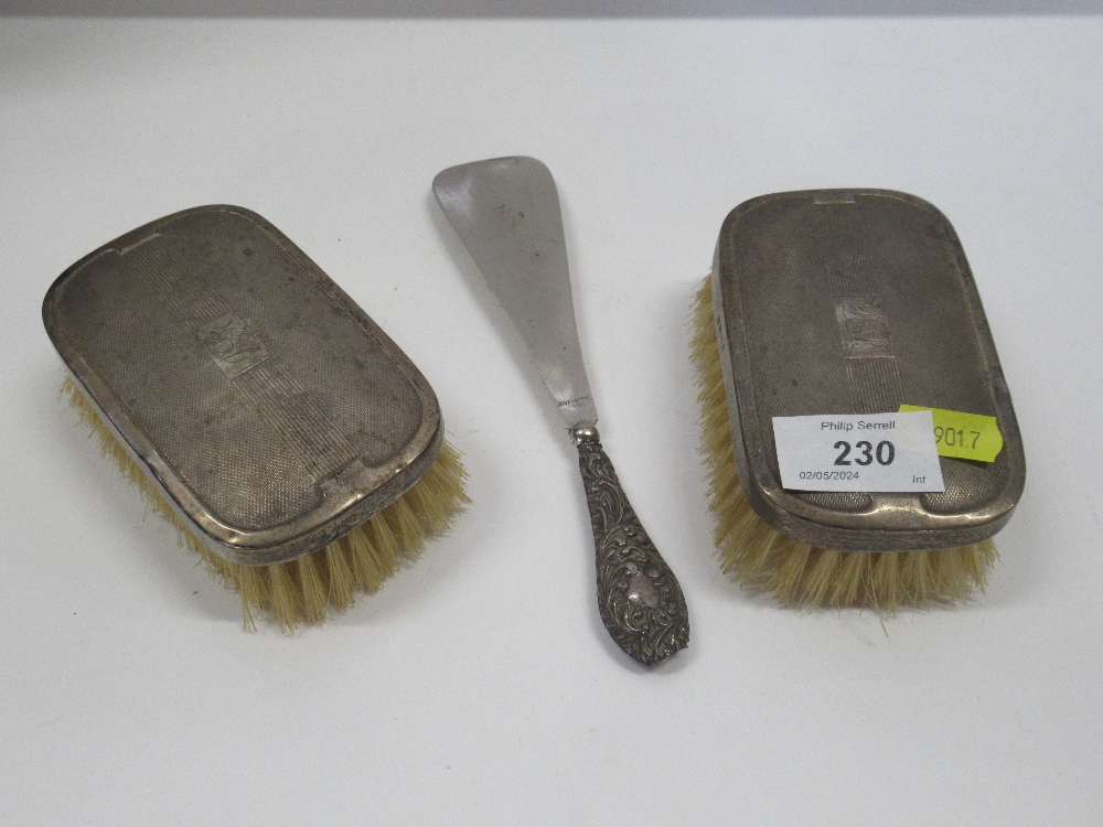A pair of silver backed brushes together with a shoe horn with silver handle