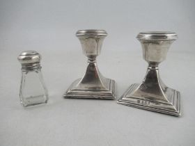 A pair of silver dwarf candlesticks, on square bases, together with a glass bottle with silver screw