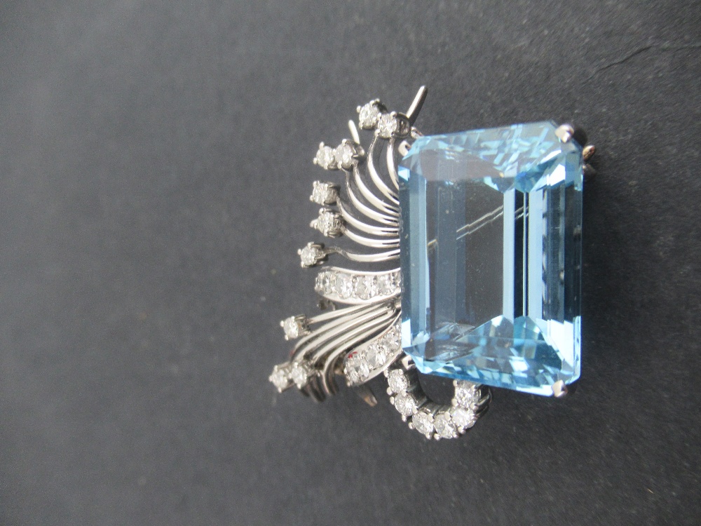 A white gold aquamarine and diamond asymmetric brooch, claw set emerald cut aquamarine, with fan