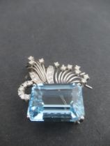 A white gold aquamarine and diamond asymmetric brooch, claw set emerald cut aquamarine, with fan