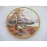 A Royal Worcester plate decorated with a view of Derwent Water by Harry Davies to a gilt boarder