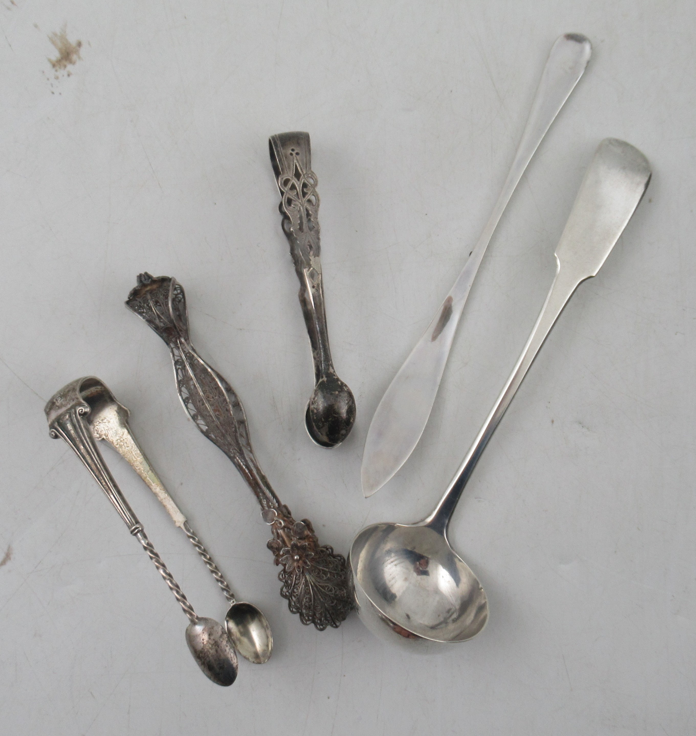A Scottish silver fiddle pattern sauce ladle, together with three sugar tongs and a butter knife,