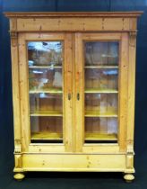 A large Victorian stripped pine bookcase, with a moulded cornice above a pair of glazed panelled