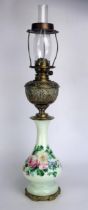 A Victorian brass and glass oil lamp, with embossed brass reservoir mounted on a green glass and