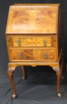 A reproduction walnut and crossbanded writing bureau, the sloping hinged fall enclosing a short