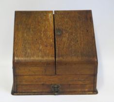 An Edwardian oak stationery box, with hinged sloping fall, enclosing slatted compartments, with