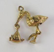 A Precious Yellow Metal Stork and Baby Pendant with articulated legs and holding a babe in swaddling