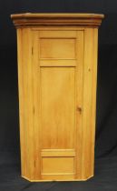 A Victorian stripped pine corner cupboard, with moulded cornice and panelled cupboard door, W