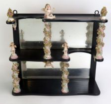 A 19th century ebonised and porcelain set of shelves with mirror panelled back, the porcelain