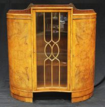 An Art Deco period walnut display cabinet of inverted serpentine outline, with central glazed door