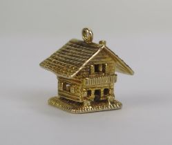 A 9ct Gold Swiss Cottage articulating to reveal a man with an alphorn, hallmarked, 5.54g