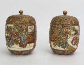 A pair of Japanese satsuma vases and covers, of cylindrical outline, decorated with panels depicting