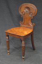 A Regency period mahogany hall chair, the shaped back with shell decoration above a solid seat