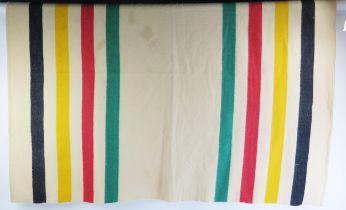 A Pendleton style wool blanket, with green, red yellow and black stripes.