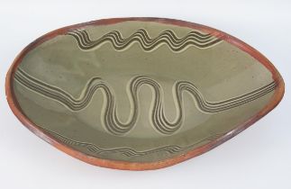 Attributed to Michael Cardew, an oval pottery dish with combed design to a two tone olive green